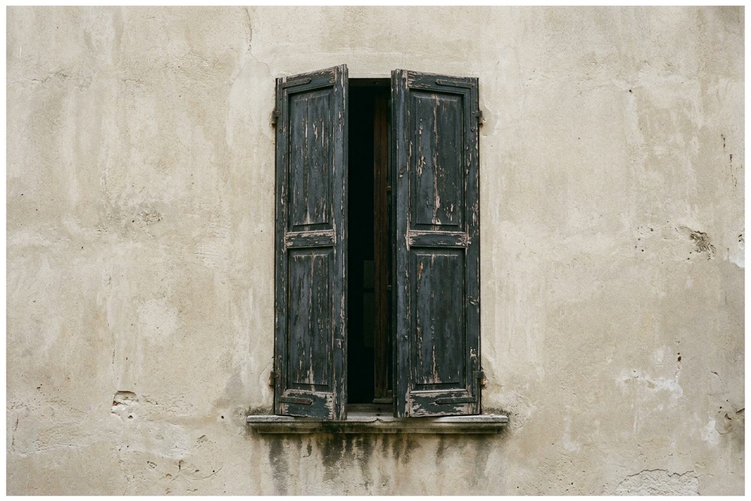 A tall shuttered window in a plain rendered wall.